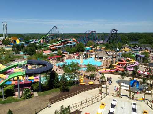 Aerial view of a vibrant water park with slides, pools, and amusement rides under a clear blue sky.