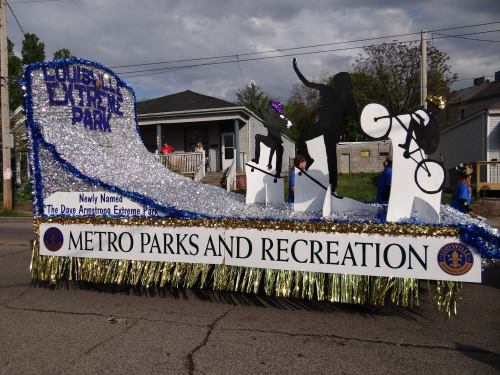 A colorful parade float featuring silhouettes of animals and cyclists, promoting the Dave Armstrong Extreme Park.