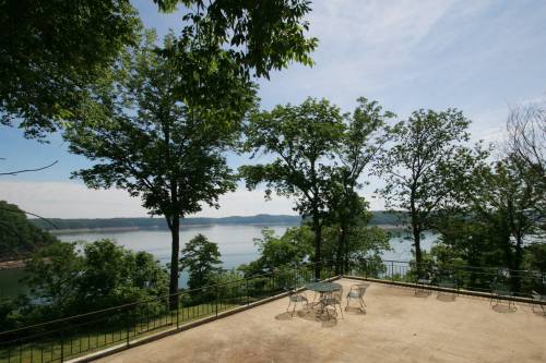 Scenic view of a lake surrounded by trees, with a patio area and clear blue sky in the background.