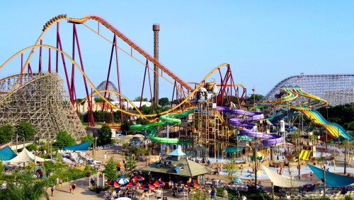 A vibrant amusement park featuring roller coasters, water slides, and a bustling crowd enjoying the attractions.