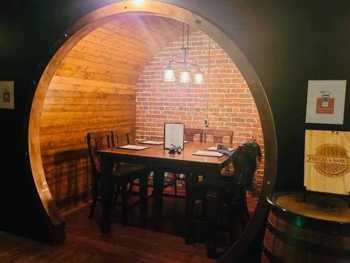 A cozy dining area with a wooden table and chairs, framed by a circular wooden arch and a brick wall.