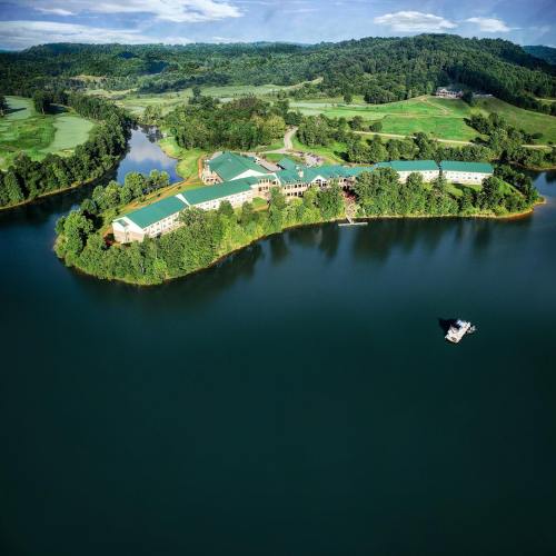 Aerial view of a lush green landscape with a lake and a resort building surrounded by trees and hills.