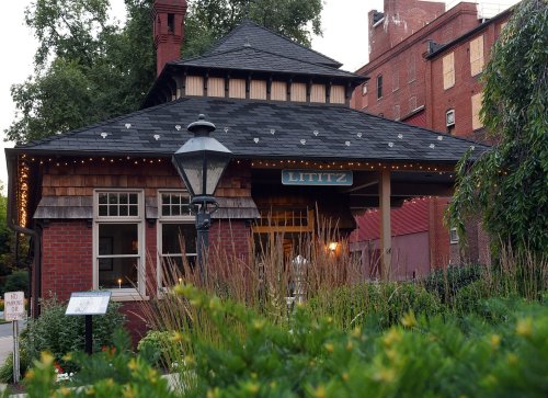 A charming brick building with a shingled roof, surrounded by greenery and soft lighting, creating a welcoming atmosphere.