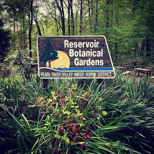 Sign for Reservoir Botanical Gardens surrounded by greenery and colorful flowers.