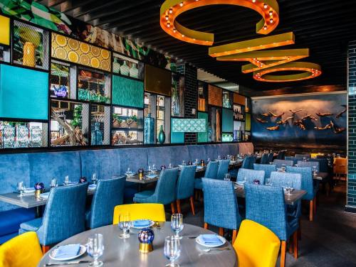 Colorful restaurant interior featuring blue seating, vibrant wall decor, and stylish table settings.