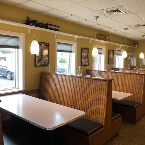 Interior of a diner featuring wooden booths, large windows, and railroad-themed decor on the walls.