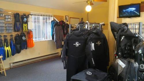 A dive shop interior featuring wetsuits, fins, and diving gear displayed on racks and walls.