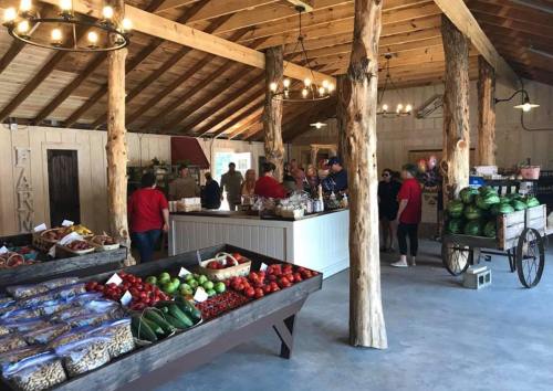 A rustic market interior with wooden beams, featuring fresh produce displays and customers browsing.