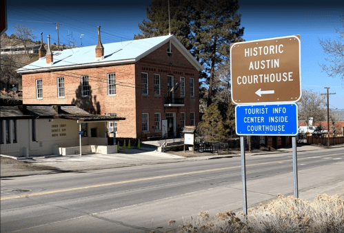 Historic Austin Courthouse with a sign for tourist information, set along a quiet road.