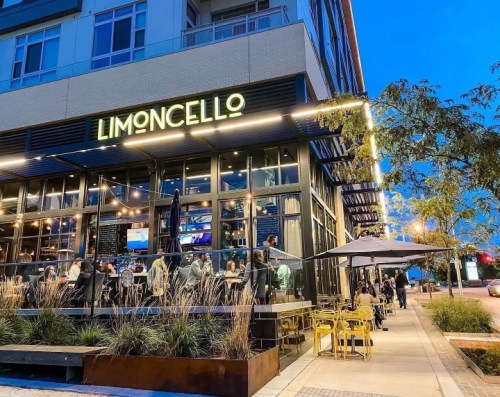 A lively restaurant named "Limoncello" with outdoor seating, illuminated at dusk, bustling with patrons.