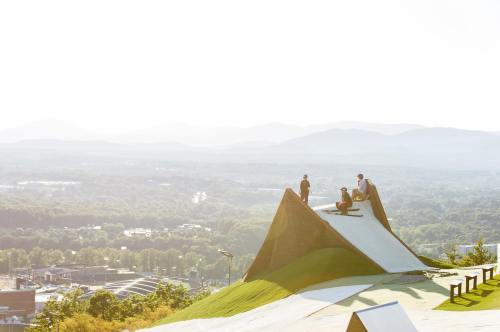 A group of people on a large, sloped ramp overlooking a scenic landscape with mountains in the background.