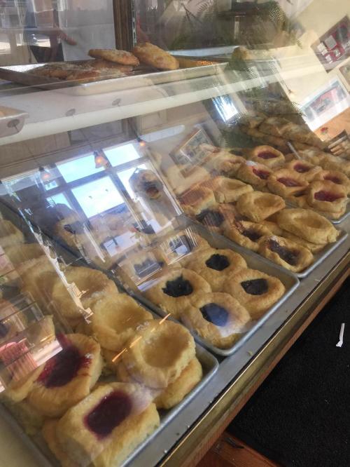 A display case filled with various pastries, including fruit-filled danishes and flaky baked goods.