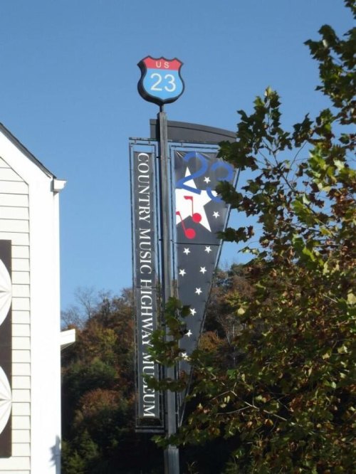Sign for US Route 23 with a banner for the Country Music Highway Museum, surrounded by trees.