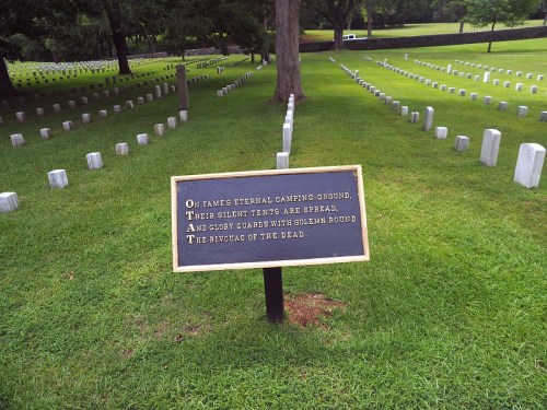 A cemetery with white gravestones and a sign that reads about eternal resting places and glory surrounding the dead.