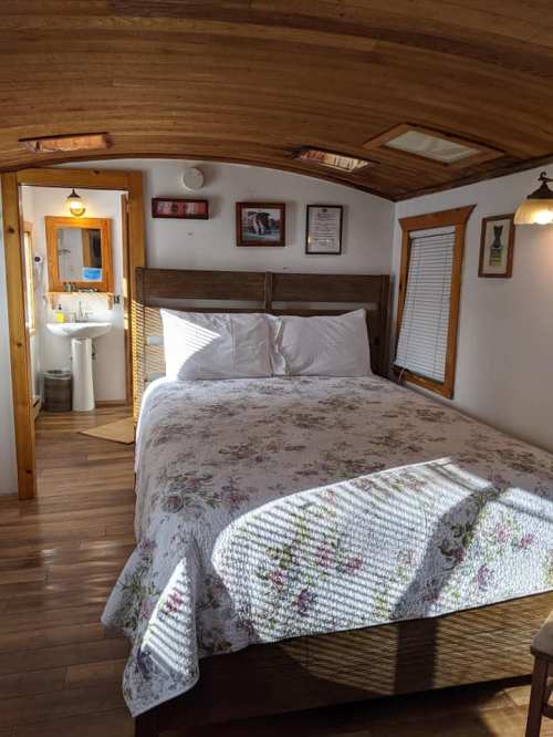 Cozy bedroom with a floral quilt, wooden accents, and natural light from skylights and windows.