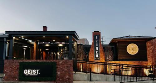 Exterior of Geist Bar & Restaurant, featuring a modern design with a sign for brunch and warm lighting at dusk.
