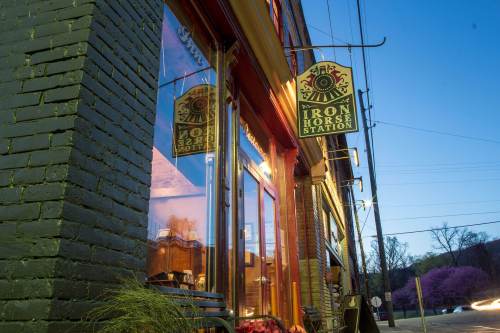 A storefront with a sign reading "Iron Horse Station," reflecting in the window, surrounded by trees and streetlights.
