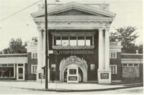 Historic building with grand columns and an ornate entrance, featuring signage for "Elton's Gardens." Black and white photo.