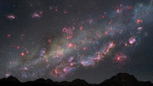 A stunning night sky filled with colorful galaxies and stars, set against a silhouette of mountain peaks.