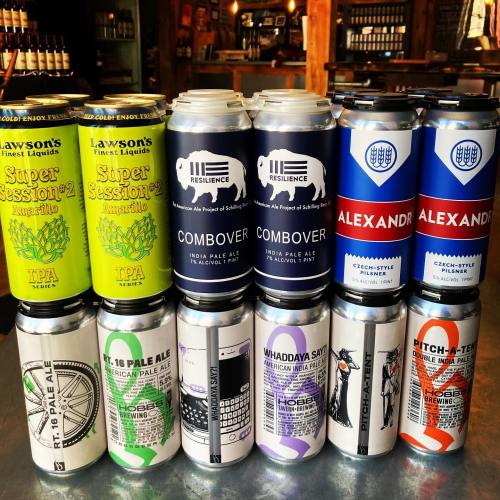 A variety of craft beer cans arranged in two rows, showcasing different styles and colorful labels.