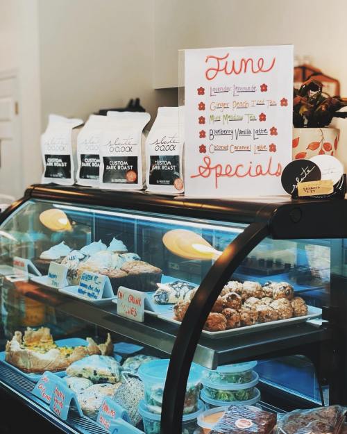 A display case filled with baked goods and a sign listing June specials at a cozy café.