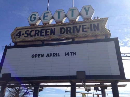 Sign for Getty 4-Screen Drive-In announcing it will open on April 14th, with a clear blue sky in the background.
