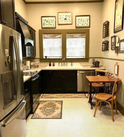 A cozy kitchen featuring black cabinets, stainless steel appliances, and a small dining table by the window.