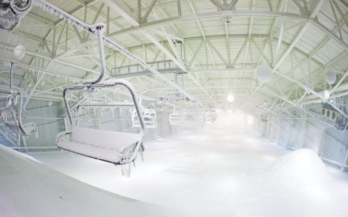 A snowy indoor ski resort with empty chairlifts and a white, powdery landscape.
