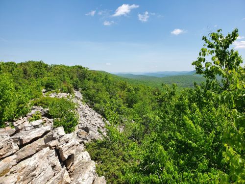 A scenic view of lush green hills and rocky outcrops under a clear blue sky.