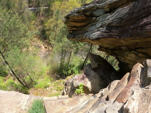 A rocky cliff edge overlooking a lush green valley and a winding road below.