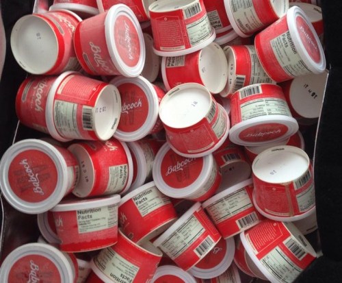 A pile of red and white ice cream containers, some with nutrition labels visible, stacked together.