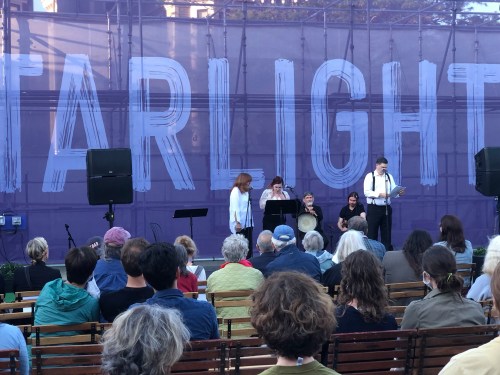A small crowd watches a live performance on stage with musicians and a large "Starlight" sign in the background.