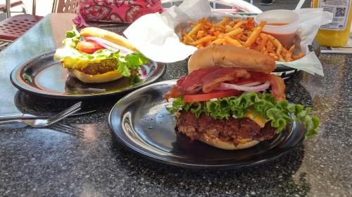 Two gourmet burgers with lettuce, tomato, and bacon, served with a side of crispy fries on a black table.