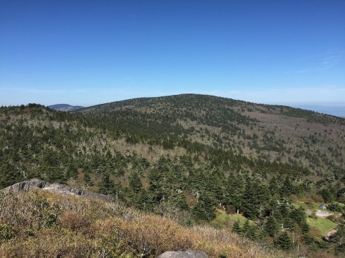 A panoramic view of a lush, green mountain landscape under a clear blue sky.