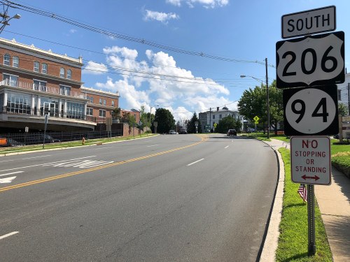 A clear road sign indicating routes 206 and 94 South, with a "No Stopping or Standing" sign nearby. Bright blue sky above.