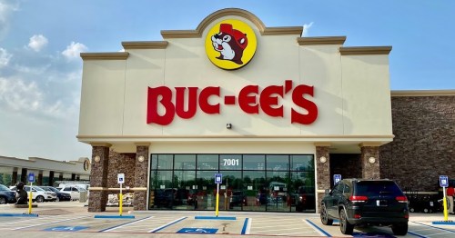 Exterior of a Buc-ee's convenience store with a large sign, blue sky, and parking lot visible.