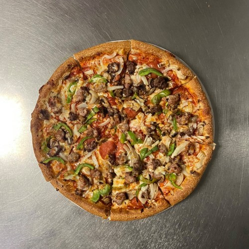 A round pizza topped with various meats, green peppers, onions, and cheese on a whole wheat crust.