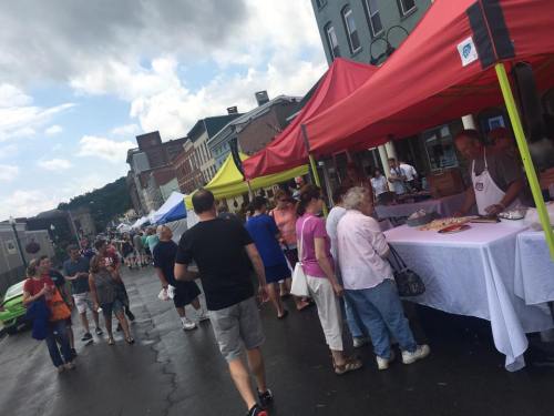 A bustling street market with colorful tents, vendors, and people browsing and enjoying the atmosphere.