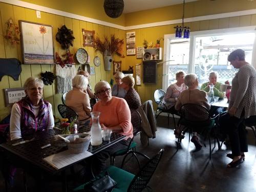 A cozy café scene with a group of older women chatting and enjoying their time together at tables.