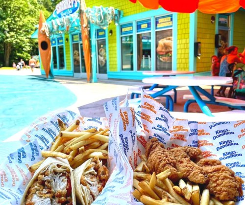 Two baskets of food with fries, featuring tacos and fried chicken, in front of a colorful restaurant.