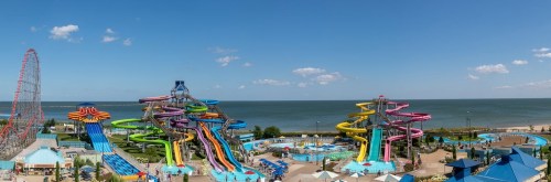 A vibrant water park with colorful slides, pools, and a view of the ocean under a clear blue sky.