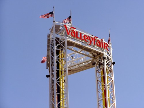 Sign for Valleyfair amusement park with American flags against a clear blue sky.