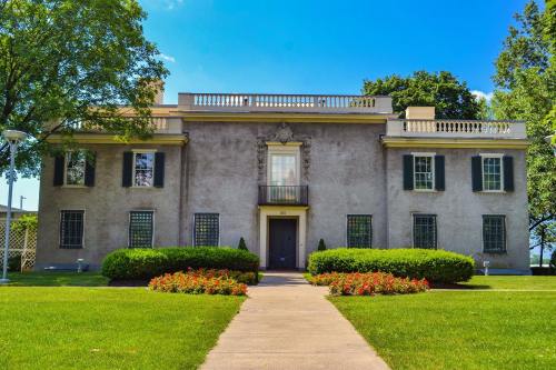 A two-story building with a balcony, surrounded by green lawns and colorful flower beds under a clear blue sky.