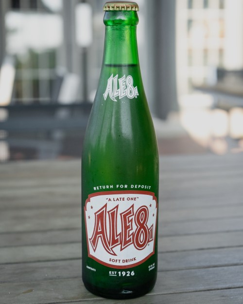 A green glass bottle of Ale-8-1 soft drink, featuring a vintage label with red and white design.