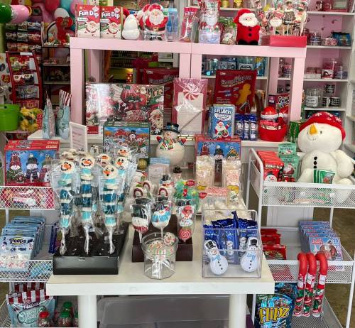 A festive display of holiday-themed candies, decorations, and toys in a colorful store setting.