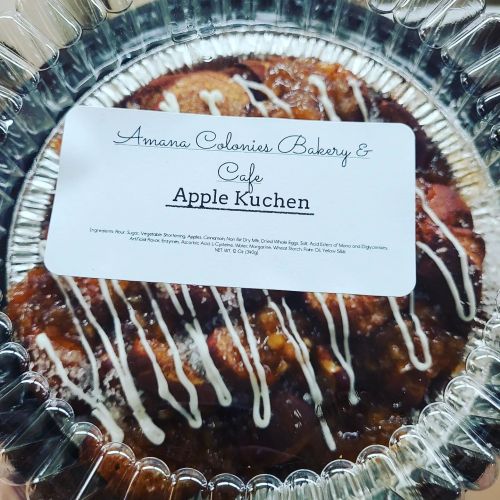 A close-up of a packaged apple kuchen from Amana Colonies Bakery & Cafe, featuring a label with ingredients.