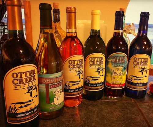 A lineup of Otter Creek Winery bottles, featuring various wines like Adirondack Red, Harvest Red, and La Crescent.