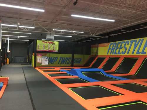 Indoor trampoline park featuring multiple trampolines, a foam pit, and colorful safety padding.