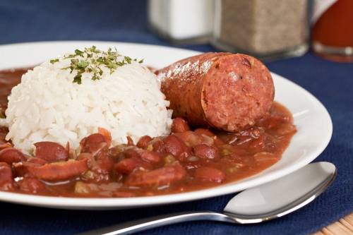 A plate of rice served with red beans and sausage, garnished with herbs, on a blue tablecloth.