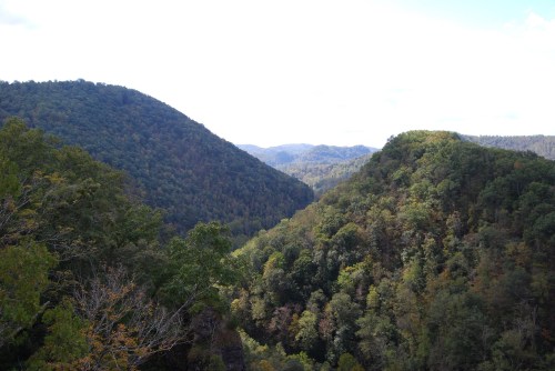 A scenic view of rolling green hills and valleys under a partly cloudy sky.